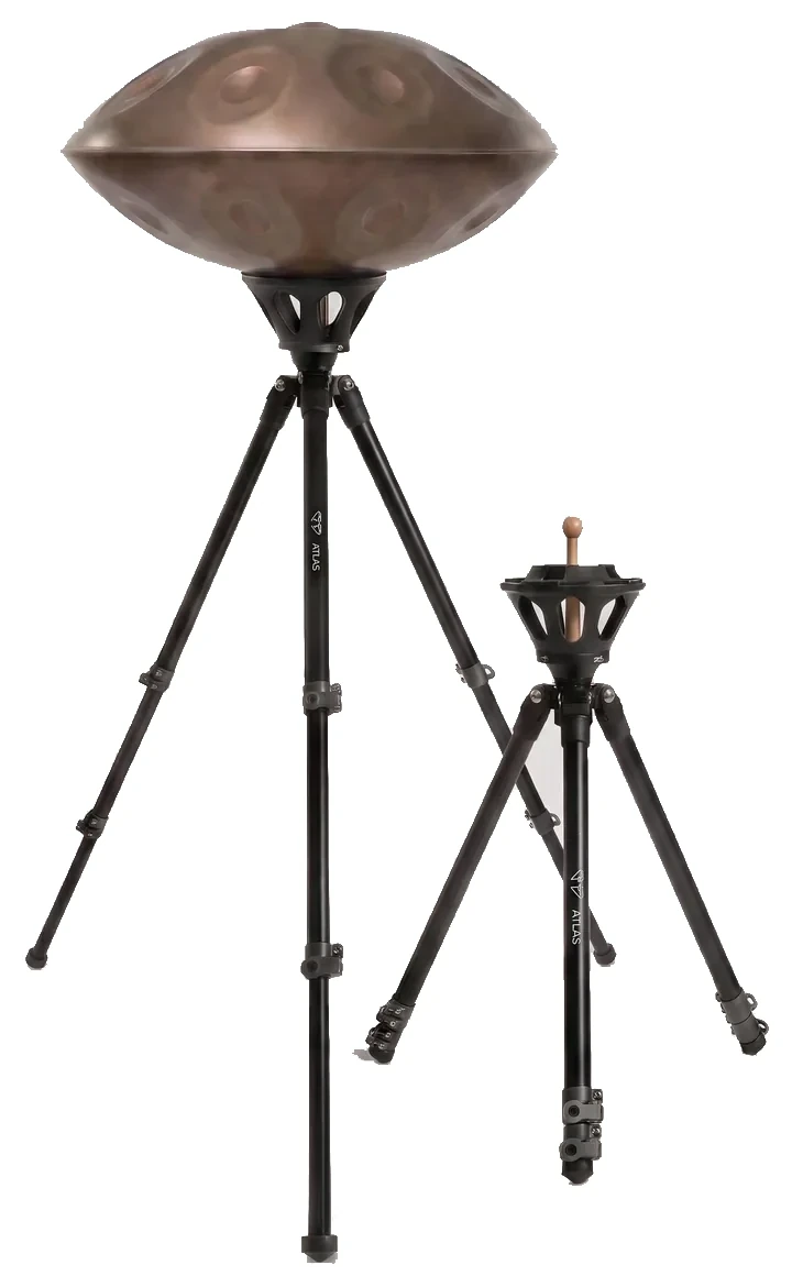 Two Atlas Pro tripods side by side on a grey background: the left one extended to its high position carrying a steel handpan, the right one set low with its legs drawn in.